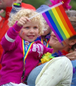 young blonde girl smiling waving rainbow flag LGBT at a 2017 Pride event in England